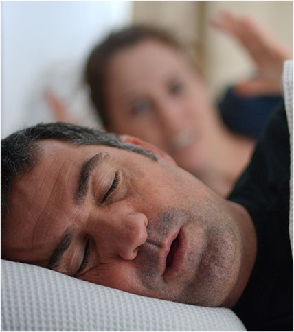Man sleeping and snoring. Woman in the background wide awake.